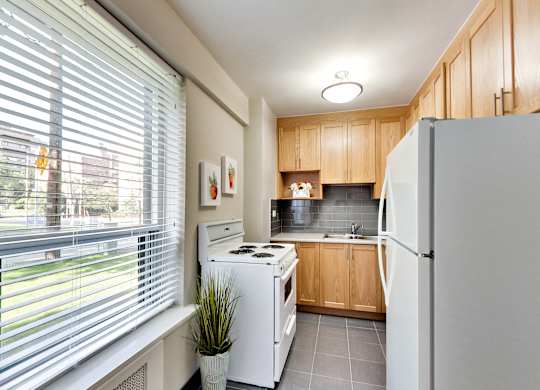 a kitchen with white appliances and wood cabinets and a large window