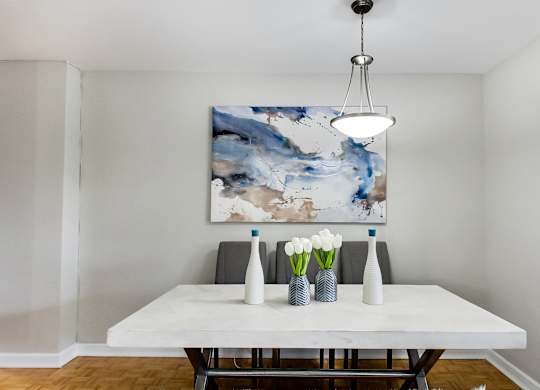 a dining room with a white table and a large abstract painting