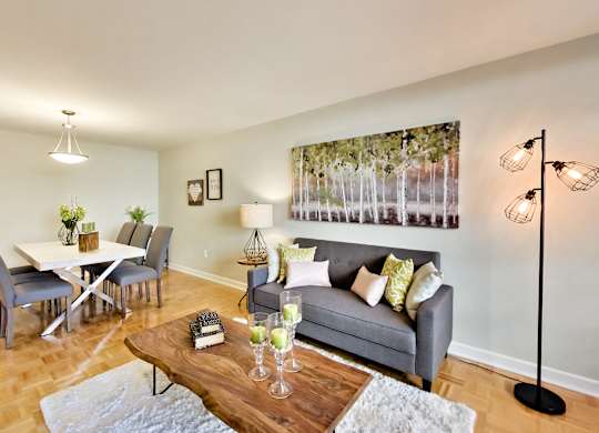 A living room with a grey couch, a wooden coffee table, and a large painting on the wall.