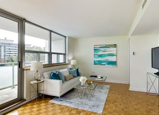A living room with a white couch and a painting on the wall.