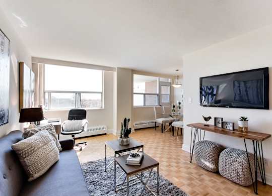 A living room with a grey couch, a black chair, a wooden table, and a television mounted on the wall.