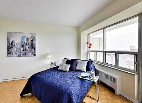 A bedroom with a blue bedspread and a painting on the wall.