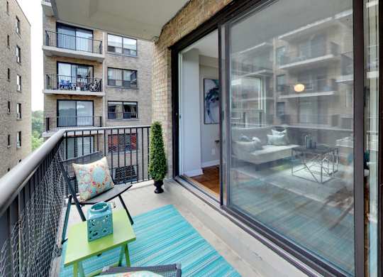 a balcony with a blue rug and chairs and a sliding glass door