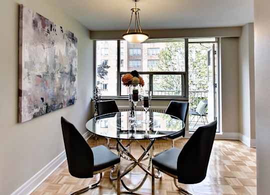 a dining room with a glass table and chairs and a large painting