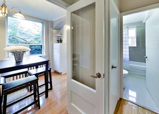 an open door leading into a kitchen and dining room with a table and chairs