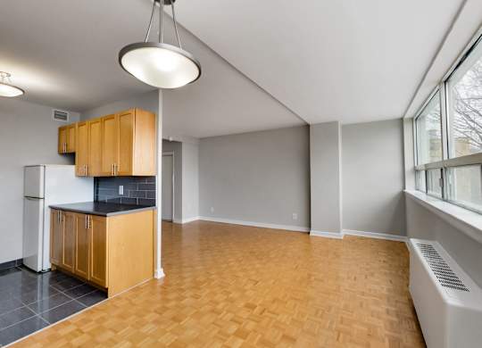 an empty living room with a kitchen and a large window
