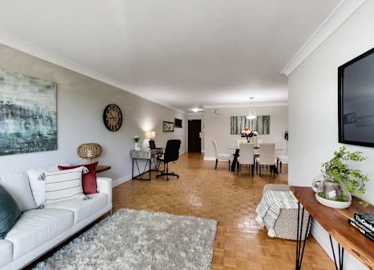 A living room with a white couch and a painting on the wall.