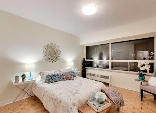 A bedroom with a bed, a table, and a window.