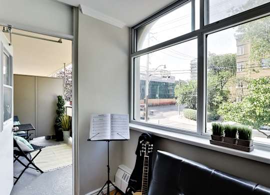 A room with a guitar, a chair, a music stand and a window.