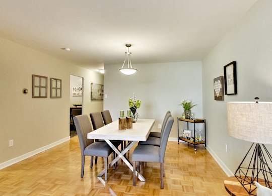 A dining room with a white table and grey chairs.