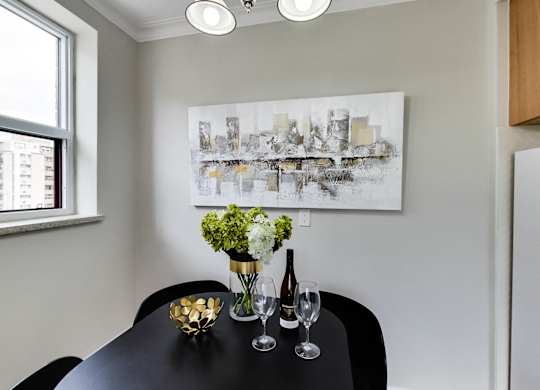 a dining room with a black table and a painting on the wall