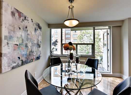 a dining room with a glass table and chairs and a large window