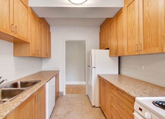 an empty kitchen with wooden cabinets and a white refrigerator