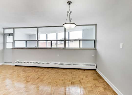 an empty living room with a large window and wood floors