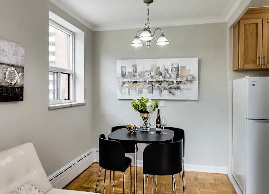 a dining room with a black table and chairs and a refrigerator