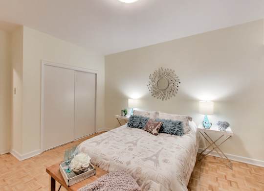 A bedroom with a bed, a table, and a wall clock.