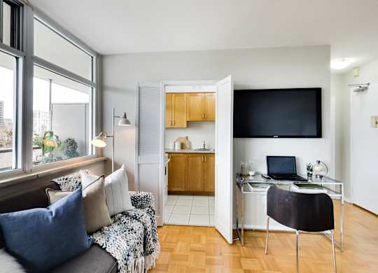 A room with a couch, a chair, a desk, and a television.