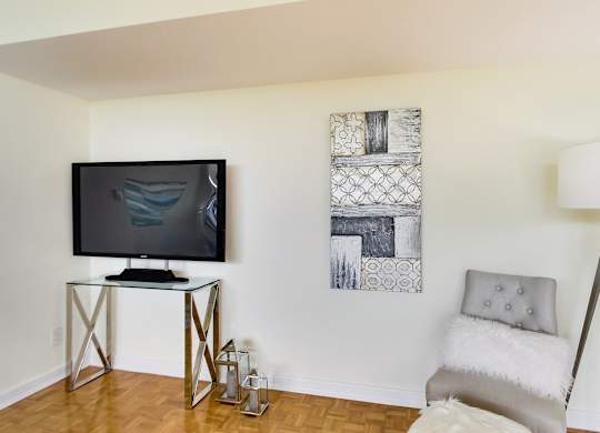 A modern living room with a television, a chair, and two pieces of artwork on the wall.