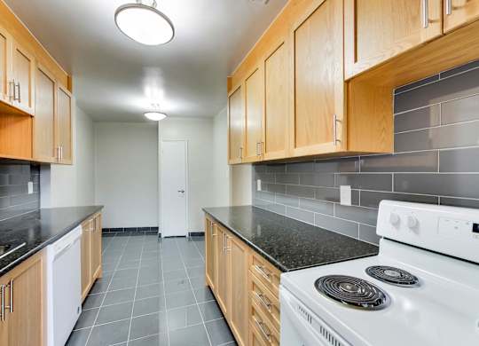 an empty kitchen with white appliances and wood cabinets