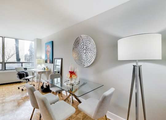 A modern dining room with a glass table and white chairs.