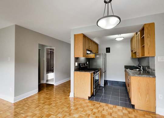 a view of an empty kitchen with wood cabinets and a stainless steel refrigerator
