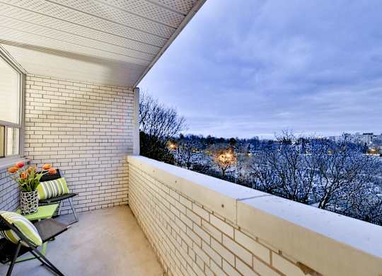 a balcony with a white brick wall and two chairs on it
