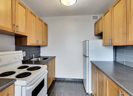 an empty kitchen with white appliances and wood cabinets