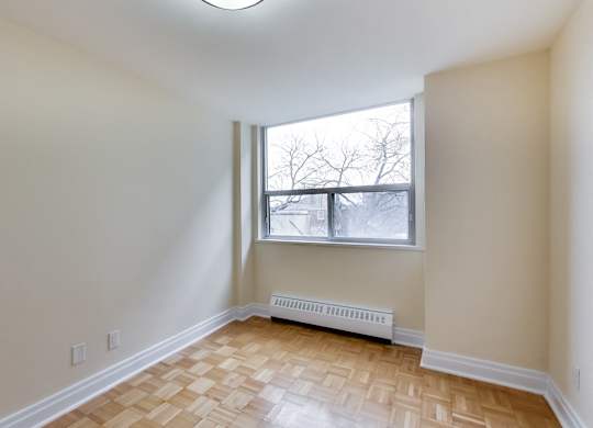 A room with a window and a radiator on the floor.