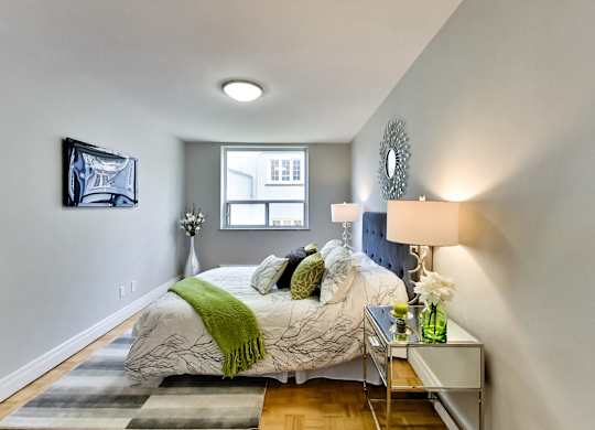 a bedroom with grey walls and a bed with green pillows