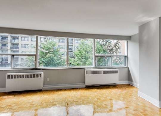 an empty living room with a large window and wood floors