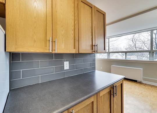 an empty kitchen with wood cabinets and a gray counter top