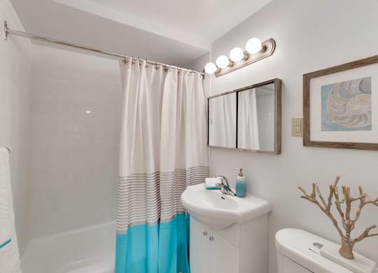 A bathroom with a white sink and a blue shower curtain.