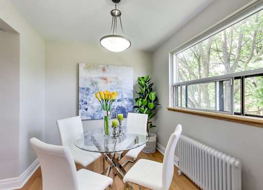 A dining room with a glass table and white chairs.