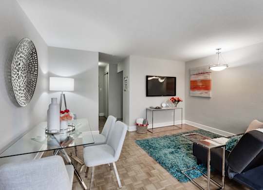 A modern living room with a glass table and white chairs.