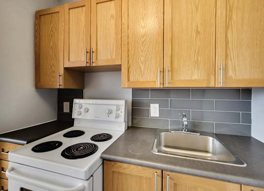 an empty kitchen with a stove sink and cabinets