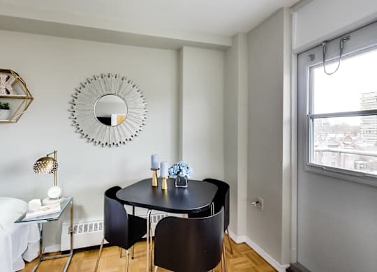 A black table with two chairs and a mirror on the wall.