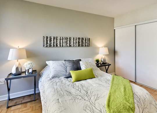 A bedroom with a bed, two lamps, and a green throw.