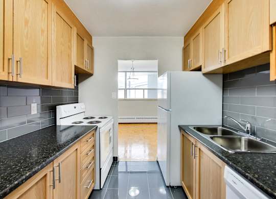 a kitchen with white appliances and black counter tops and wooden cabinets