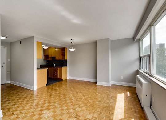 an empty living room with wood flooring and a kitchen