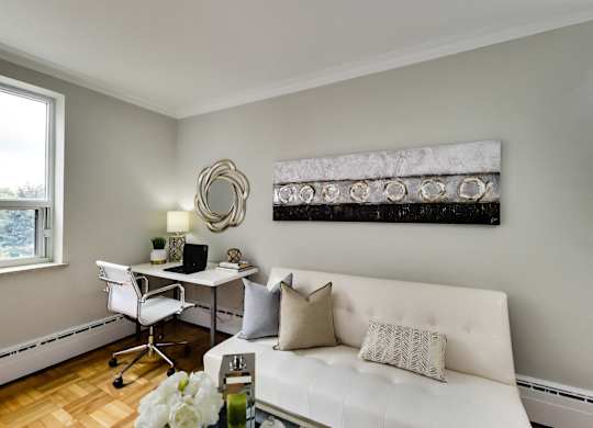 a living room with a white couch and a desk with a chair