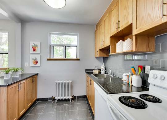 A kitchen with a white stove top oven and wooden cabinets.