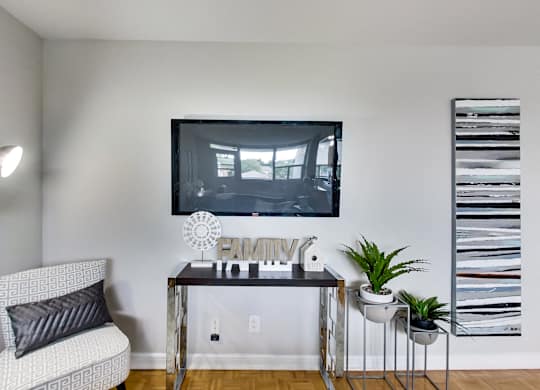 a living room with a tv hanging on the wall and a table with a chair