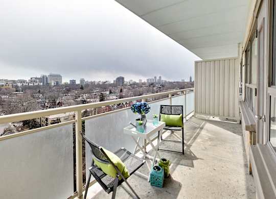 A balcony with a table and chairs overlooking a city.