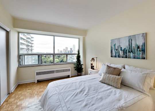 A bedroom with a large bed and a cityscape painting on the wall.