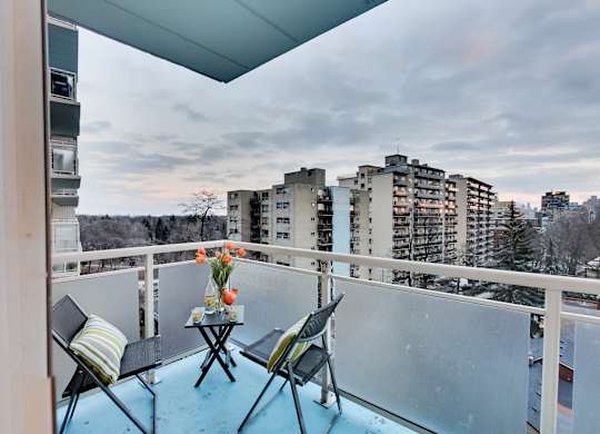 A balcony with a table and chairs overlooking a cityscape.