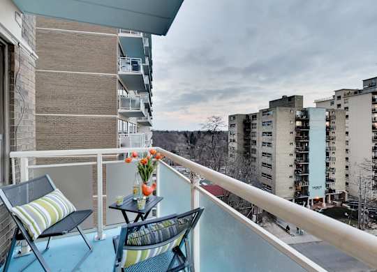 A balcony with two chairs and a table with flowers on it.