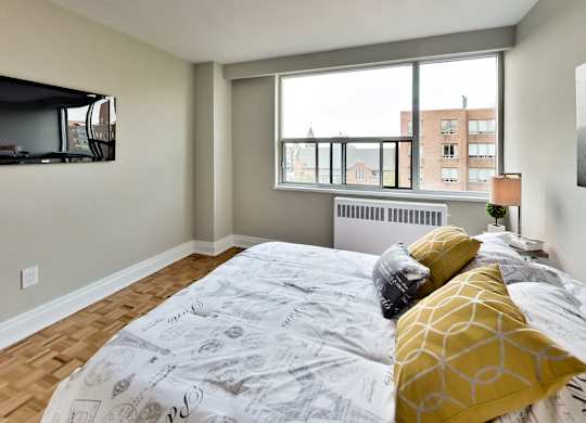 a bedroom with a large window and a bed with yellow pillows