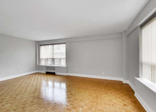 an empty living room with wood flooring and a window