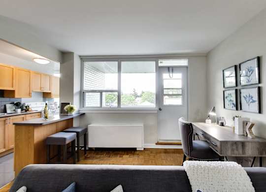 a living room with a couch and a table and a kitchen with a window