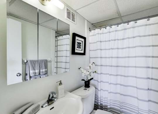 A white sink with a mirror above it and a towel hanging on the wall.